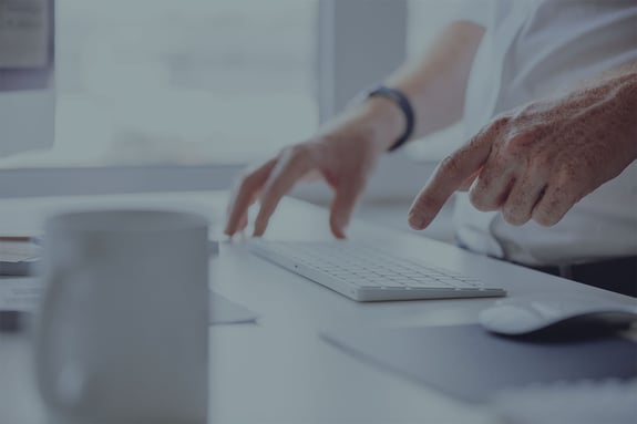 hands typing on a keyboard with one finger pointing to the key