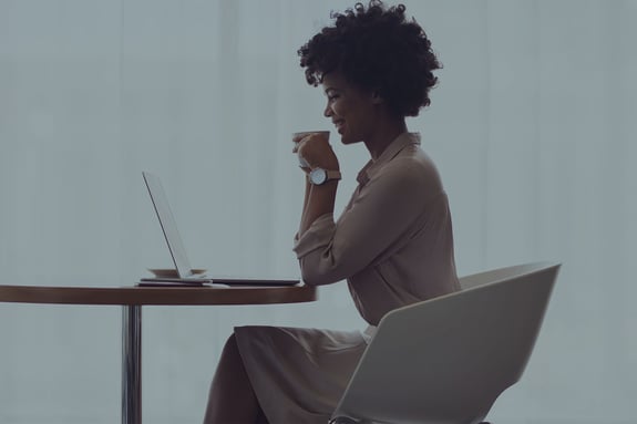 view from side of woman sitting at table looking at laptop